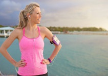 Pretty blonde women standing on beach in exercize clothes with iPhone
