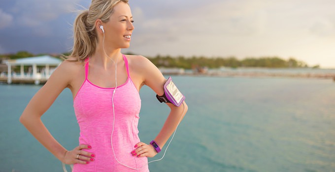 Pretty blonde women standing on beach in exercize clothes with iPhone