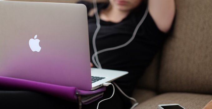 College student on couch with MacBook Pro and iPhone