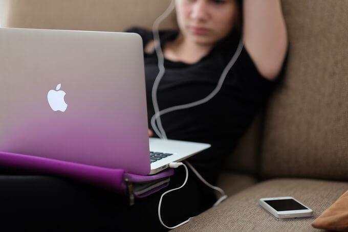 College student on couch with MacBook Pro and iPhone