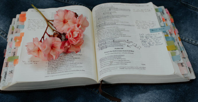 Open bible with handwritten notes and flowers on top