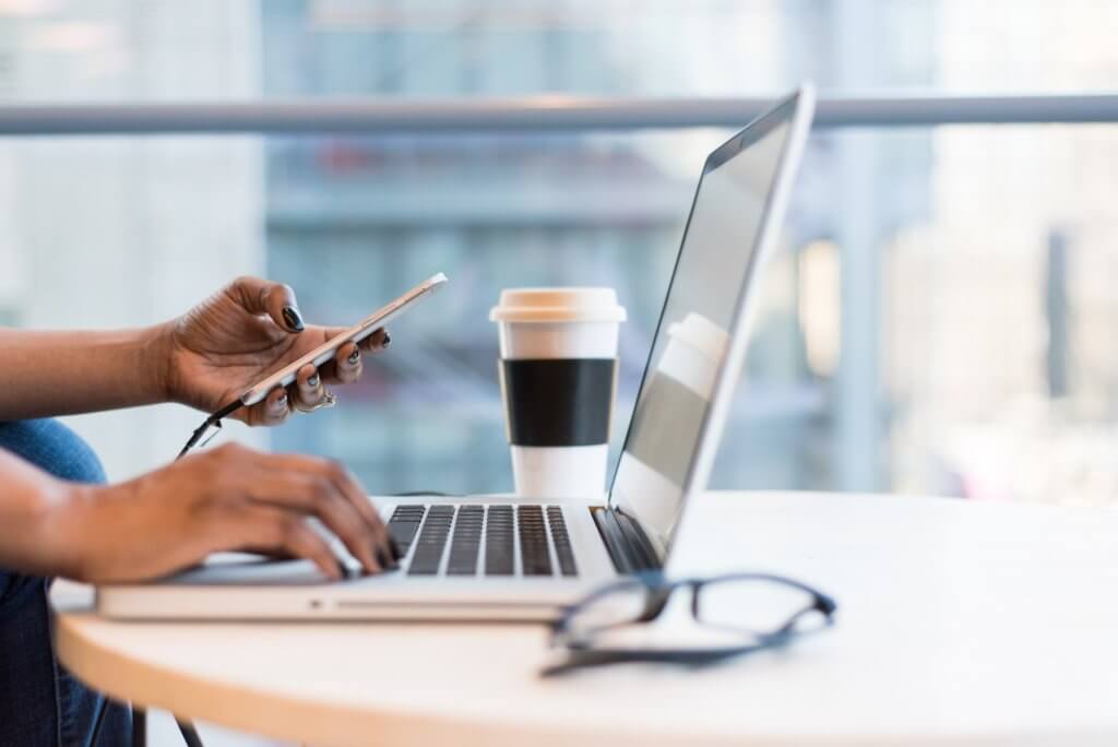 Freelance gear: A resilient smartphone Woman using a smartphone and laptop while freelancing at a coffee shop