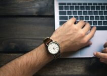 person wearing brown and white watch waiting for MacBook