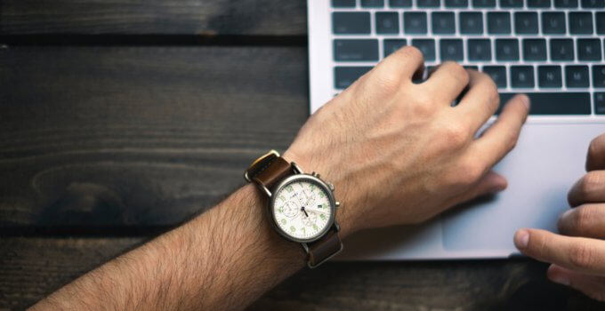 person wearing brown and white watch waiting for MacBook