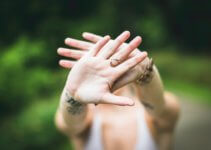 selective focus photo of person's hand with gold-colored ring in it