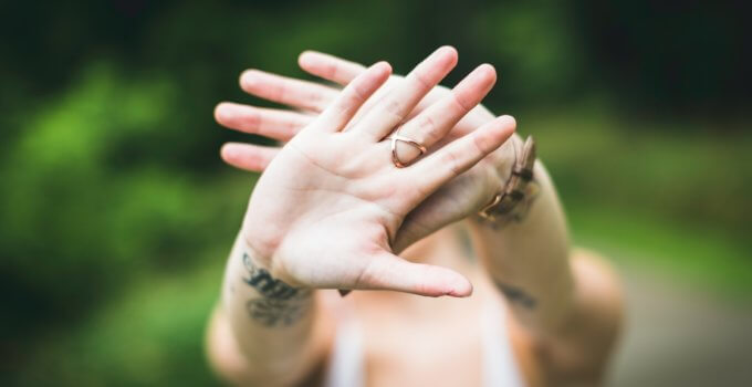 selective focus photo of person's hand with gold-colored ring in it