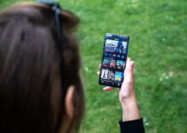 woman holding black android smartphone watching videos