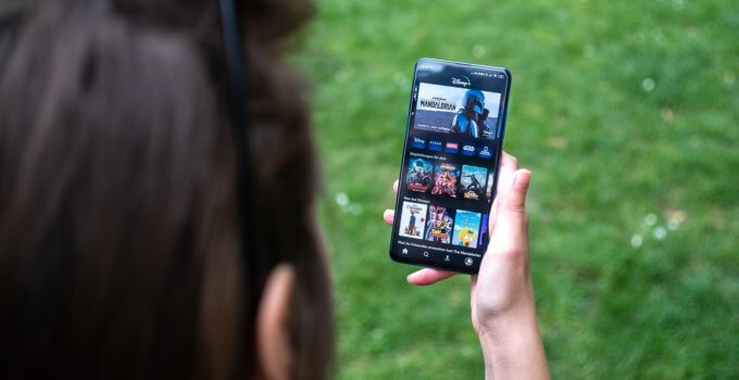 woman holding black android smartphone watching videos