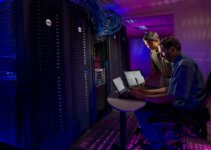 Two people migrate data between servers from server room