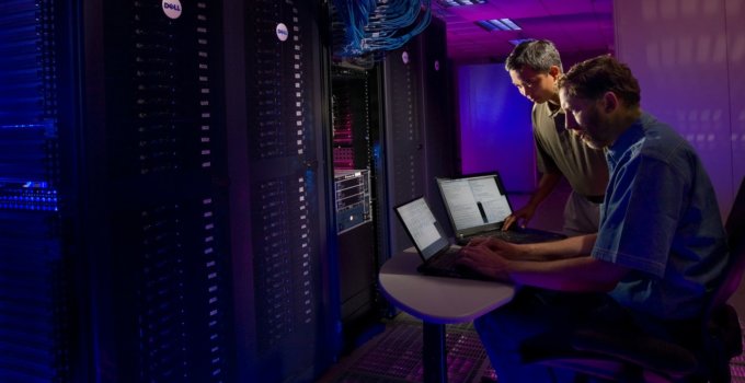 Two people migrate data between servers from server room