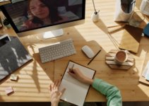 Woman writing in journal on desk with Mac