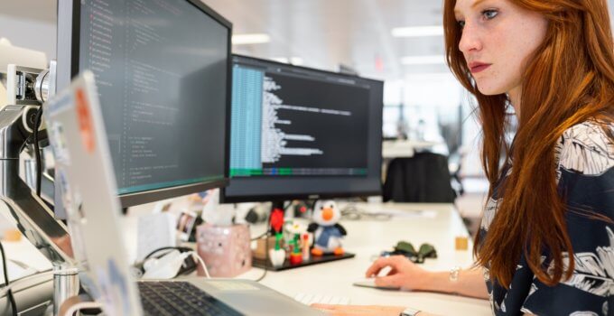 woman in green shirt using usenet in front of computer