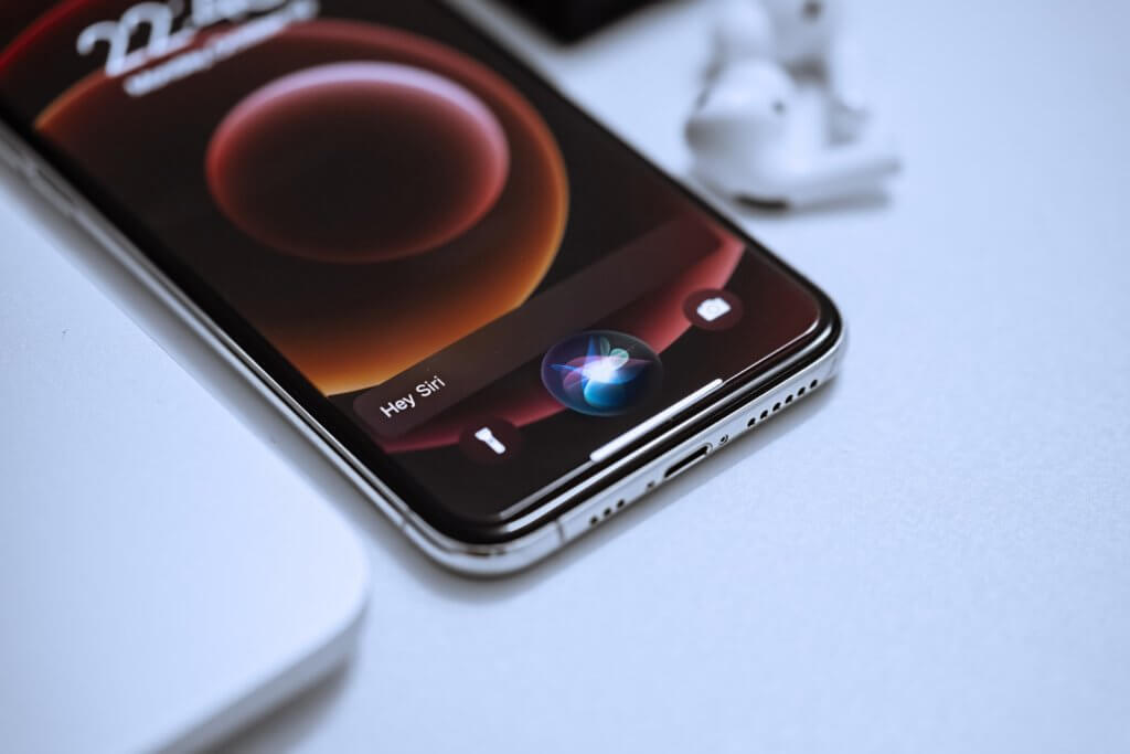 iOS smartphone on white table with Siri activated