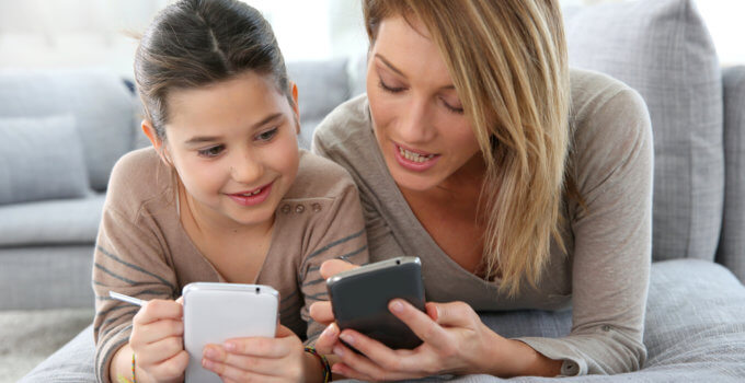 Mother and daughter playing games with smartphone