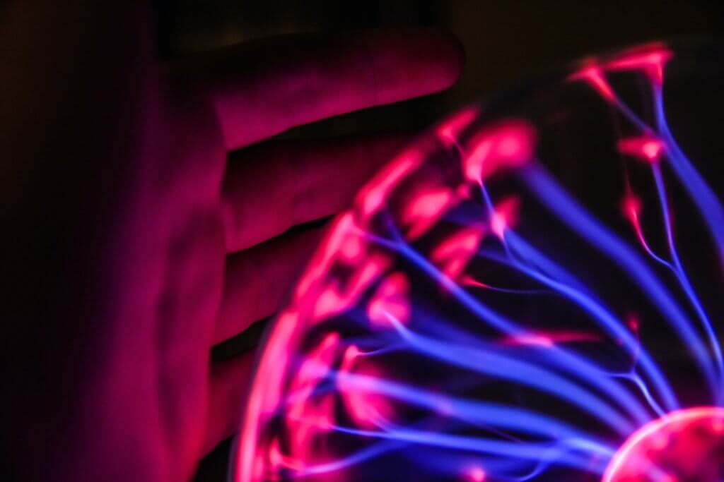Person's hand beside plasma ball signifies the coming technology boom