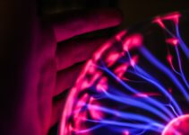 Person's hand beside plasma ball signifies the coming technology boom