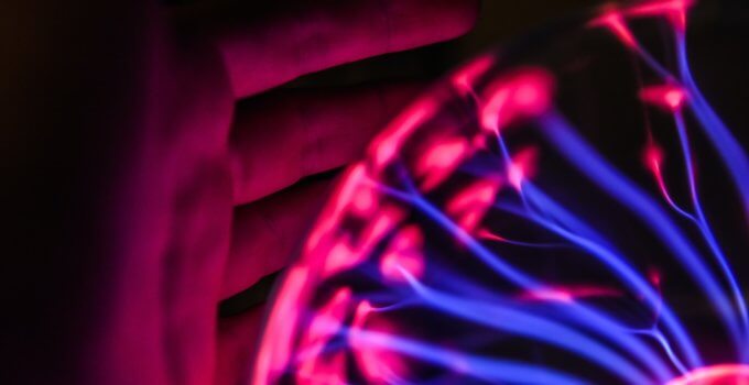 Person's hand beside plasma ball signifies the coming technology boom