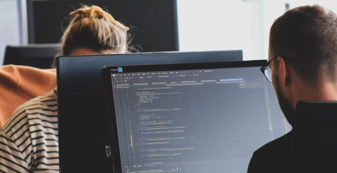 Man and woman coding at their computers