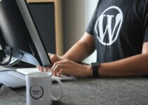 man in black and white WordPress t-shirt using computer to blog