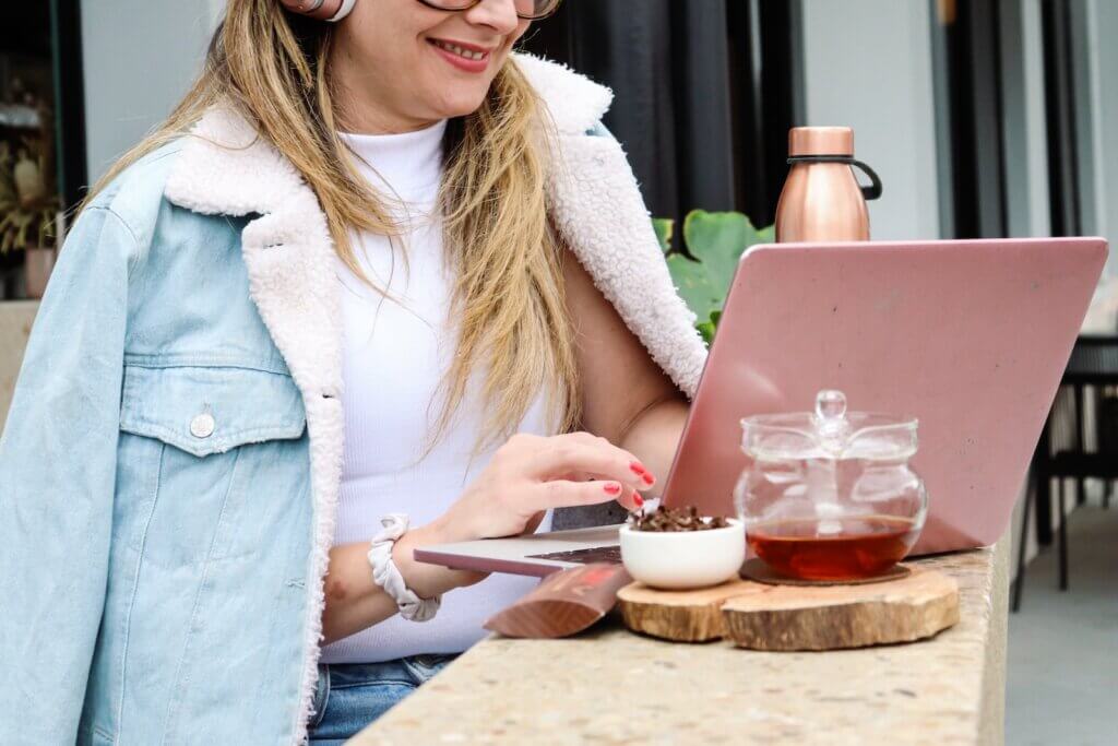 Woman freelancing with her freelance gear Woman in white cardigan freelancing at a cafe
