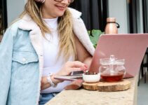 Woman in white cardigan freelancing at a cafe