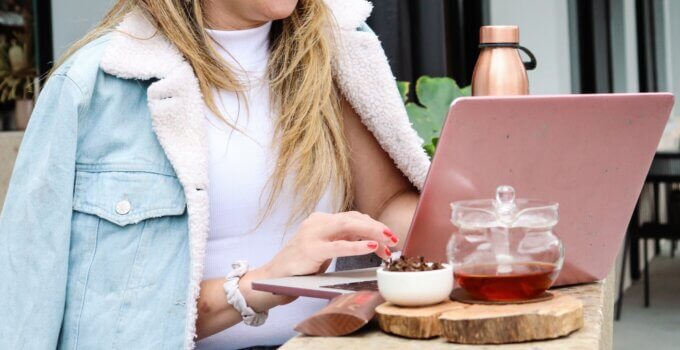 Woman in white cardigan freelancing at a cafe