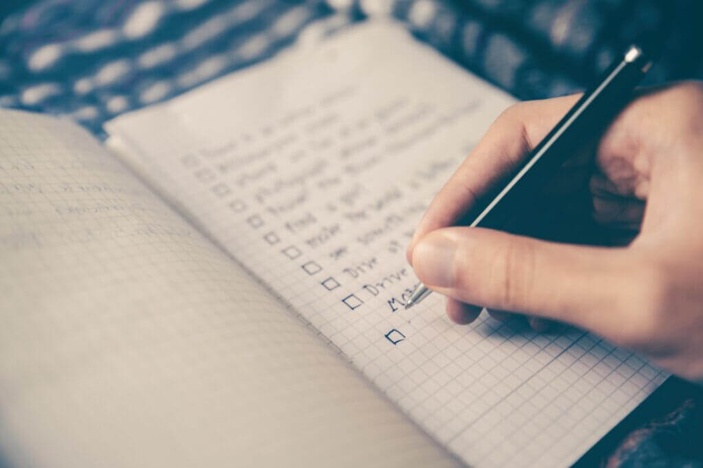 Person writing website audit checklist on a notepad