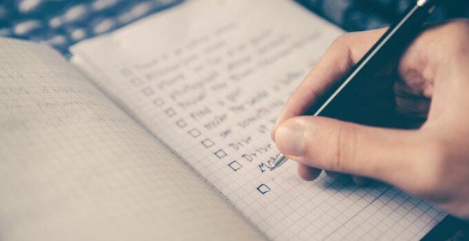 Person writing website audit checklist on a notepad