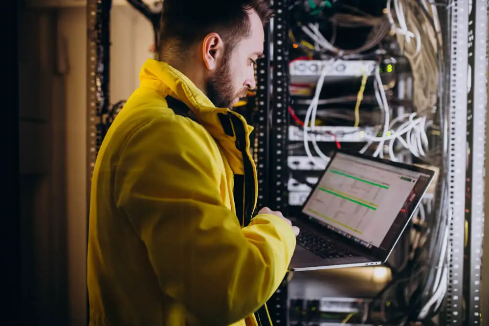 Engineer reviewing hyper converged infrastructure settings on a laptop inside a data center