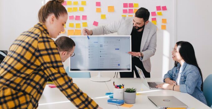 Man pitching ideas to his team in front of flat screen TV to prepare for investor meeting