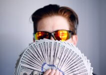man in black framed sunglasses holding fan of money