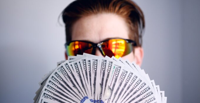 man in black framed sunglasses holding fan of money