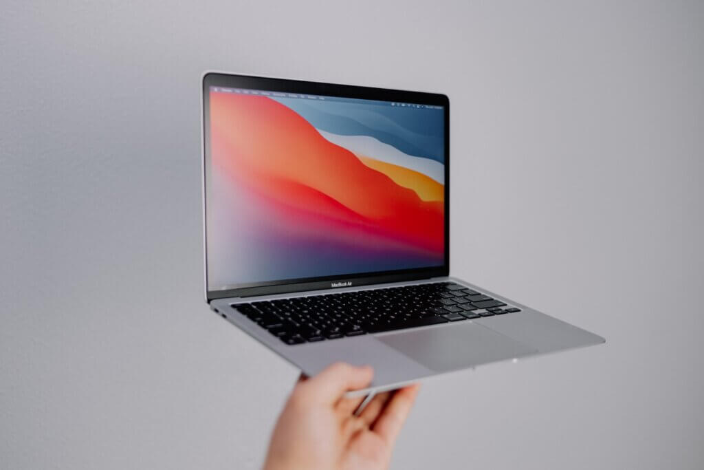 Apple MacBook Air held by a person's hand in the air