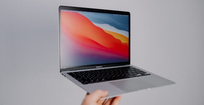 Apple MacBook Air held by a person's hand in the air