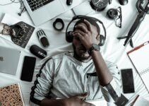 man-laying-down-thinking-multiple-gadgets