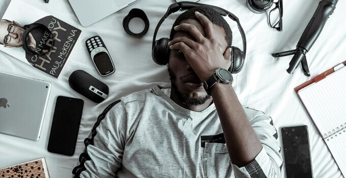 man-laying-down-thinking-multiple-gadgets
